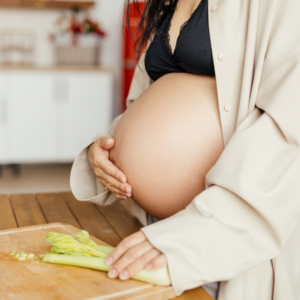 Gravid kvinde i gravid uge 39 i køkken med skærebræt