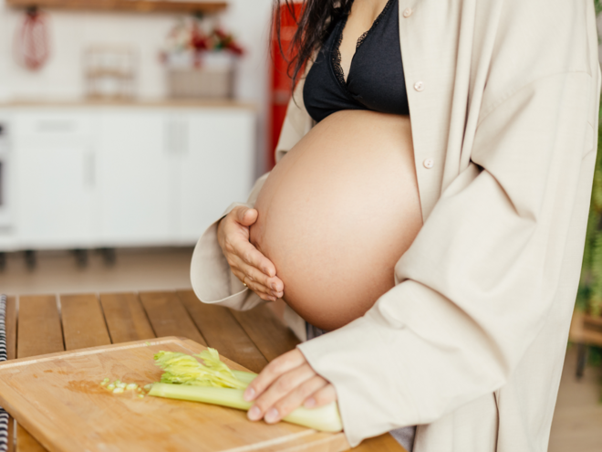 Gravid kvinde i gravid uge 39 i køkken med skærebræt